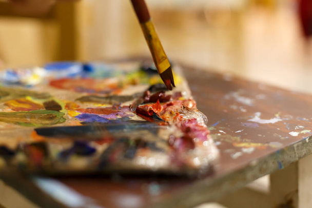 Close-up of an easel with paints, the artist paints a brush. Painting a picture - Fotó, kép