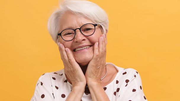 Muotokuva emotionaalinen hymyilevä vanhempi onnellinen nainen kädestä poskillaan - Valokuva, kuva