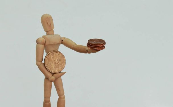Holzfigur hält einen Dollar in der Hand und verschenkt Cent - Foto, Bild