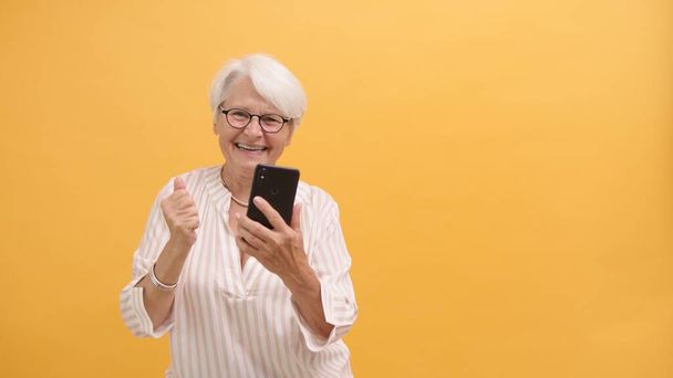Ευτυχισμένη ηλικιωμένη κυρία που κρατάει smartphone. Καλά νέα. - Φωτογραφία, εικόνα