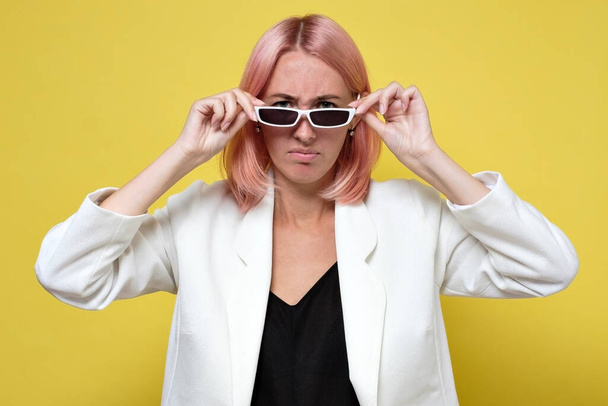 Young serious woman looking at camera through sunglasses - Valokuva, kuva