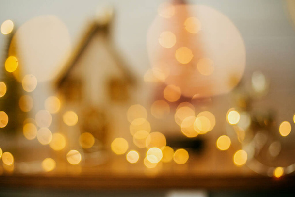 Fundo de Natal abstrato. Imagem borrada de árvores de casa e brilho em luzes festivas douradas. Bokeh iluminação amarela na aldeia de fadas em miniatura. Feliz Natal e Boas Festas - Foto, Imagem