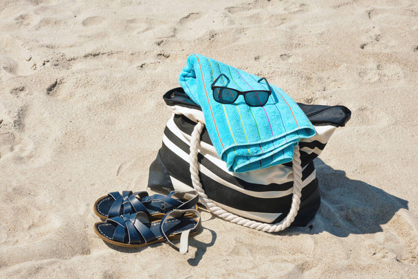 Set of personal belongings lying on the beach sand with in bright summer day  - Photo, Image