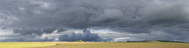Storm clouds over the fields. Landscape at sunset. Tragic gloomy sky. Panorama. The sun is hidden. - Photo, Image