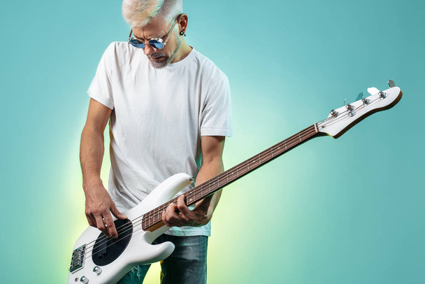 Professional musician hipster man play white bass guitar in neon lights. Rock music concept. Rock star. - Fotografie, Obrázek