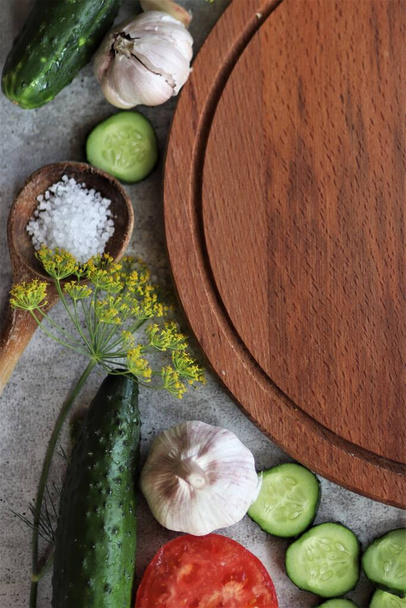 wooden cutting board among tomatoes and cucumbers - Фото, изображение