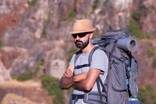 Vista orizzontale di un escursionista ispanico maschio con occhiali da sole e uno zaino pieno - Foto, immagini