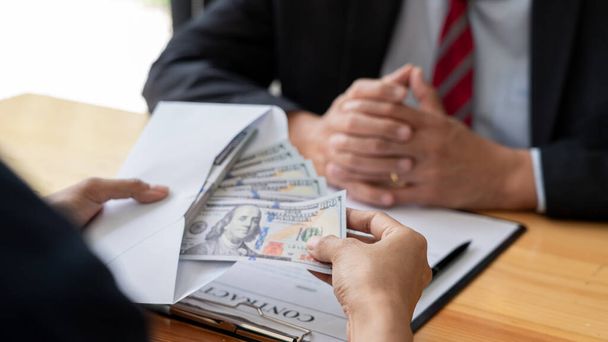 Businessman reciving money United States Dollars bills to corruption from his partner in business at working desk - bribery concept - Photo, image