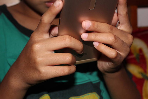 Πορτρέτο ενός χαριτωμένου ασιατικό αγόρι κρατήσει smartphone και αναζητούν περίεργα στο smartphone σε λευκό φόντο, κοντά - Φωτογραφία, εικόνα