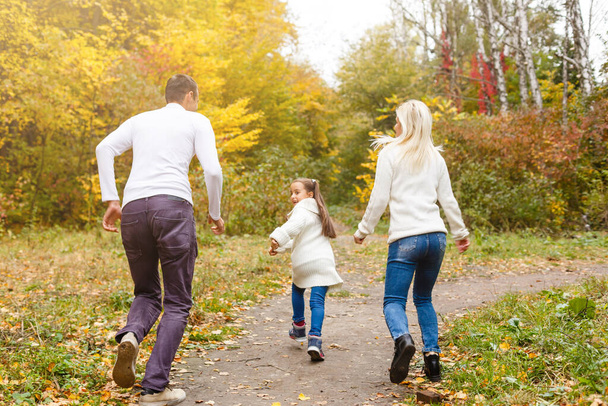 Family with child go in autumn park - Valokuva, kuva