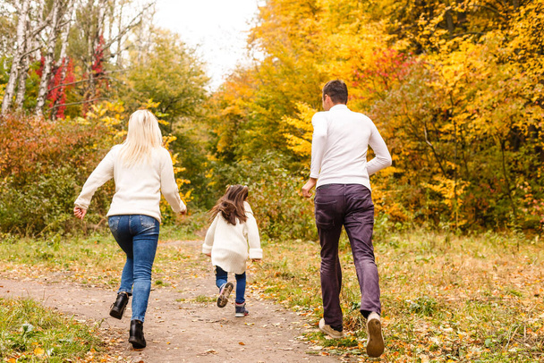 Imagem da família encantadora no parque de outono, pais jovens com boa filha adorável jogando ao ar livre, divirta-se no quintal no outono, família feliz desfrutar da natureza outonal - Foto, Imagem