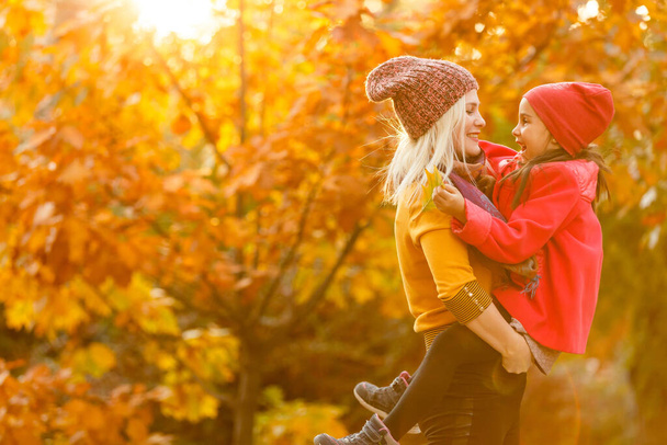 young beautiful mother and her little daughter in the autumn park - 写真・画像