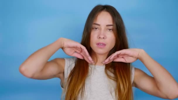 Beautiful funny woman in gray T-shirt is dancing on blue background with copy space. 4K slow motion footage - Felvétel, videó