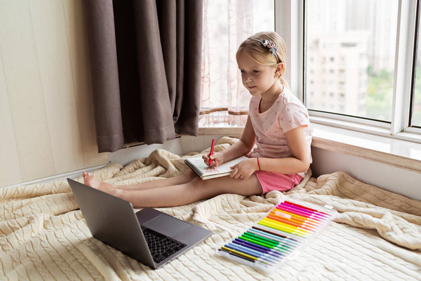 Little child english online at home. Homeschooling and distance education for kids. Girl student drawing english letters at the notebook during coronavirus covid-19 quarantine. High quality photo - Fotoğraf, Görsel