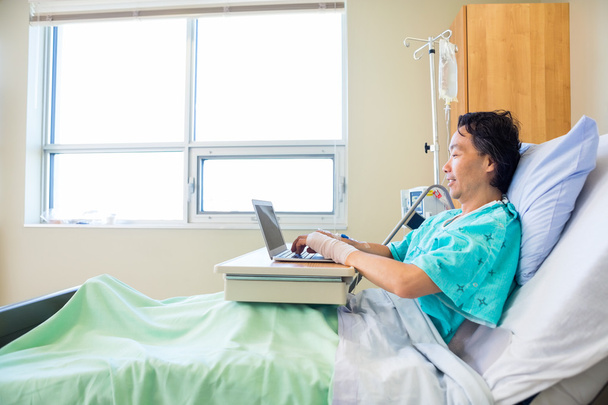 Paciente usando laptop na cama do hospital
 - Foto, Imagem