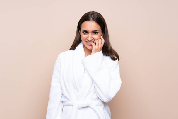 Young girl in a bathrobe over isolated background nervous and scared - Фото, изображение