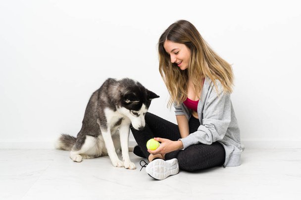 Young sport girl with her dog sitting on the floor - Photo, Image