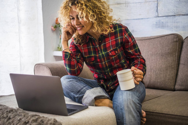 Muotokuva aikuisten kaunis nainen kotona käyttää kannettavaa tietokonetta istuu sohvalla  - Valokuva, kuva