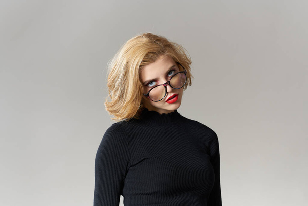 Ragazza bionda con occhiali labbra rosse camicetta nera vista ritagliata glamour luce sfondo studio - Foto, immagini