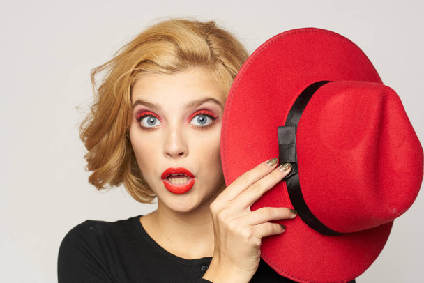 Χαριτωμένο ξανθό κοντά μαλλιά κόκκινο καπέλο στο χέρι γκρο πλαν φως φόντο - Φωτογραφία, εικόνα