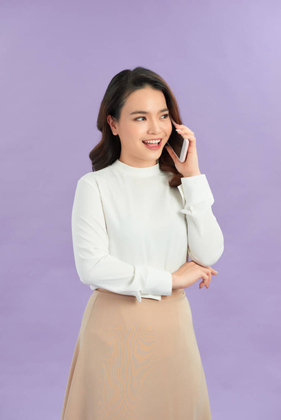 Portret van een lachende jonge casual aziatische meisje praten op mobiele telefoon - Foto, afbeelding