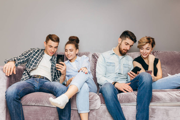 friends with mobile phones are sitting on the couch and ignoring each others - Fotoğraf, Görsel