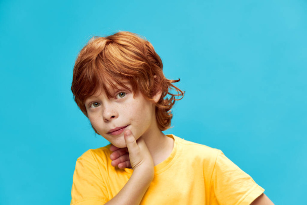 a red-haired boy with an interested look and a yellow T-shirt  - Photo, Image