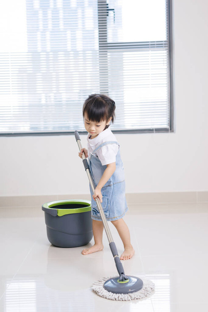 Petite fille qui nettoie le salon. Concept de ménage. - Photo, image