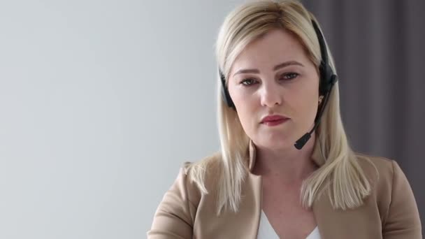 Confident female office worker wears headset conference video calling looking at laptop computer. Young businesswoman customer service manager speaking to webcam communicating in distance remote chat. - Footage, Video