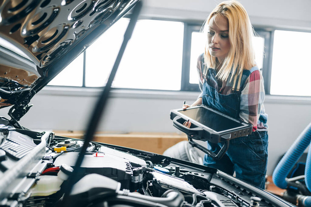 young woman checking fuel economy, car timing, and performance characteristics. - Photo, Image