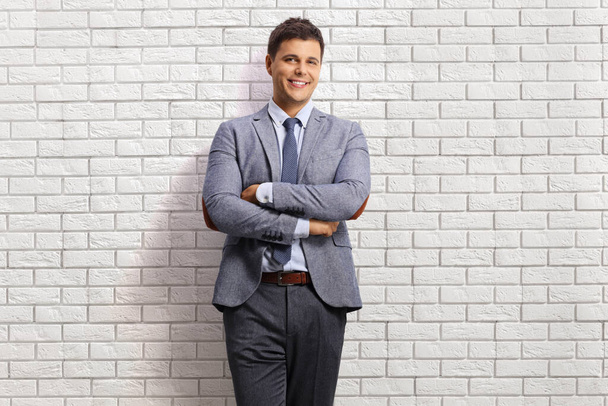 Professional young man posing on a white brick wall and smiling at the camera - Foto, imagen