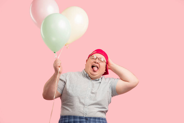 Funny tubby guy with positive emotions smiling happily, holding air balloons. - Foto, Bild