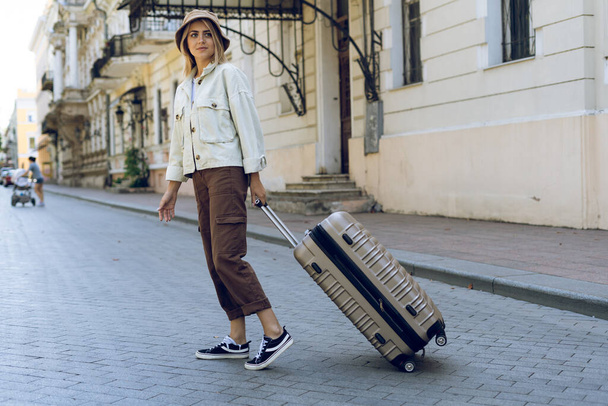 Туристка гуляет с чемоданом по улице в европейском городе, туризм в Европе. Место для смс. Копирование пространства. - Фото, изображение