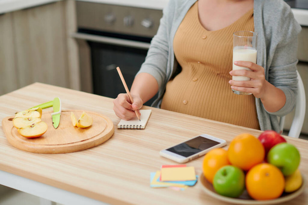 Pregnant woman holding glass milk expectant mother posing in kitchen - Photo, Image