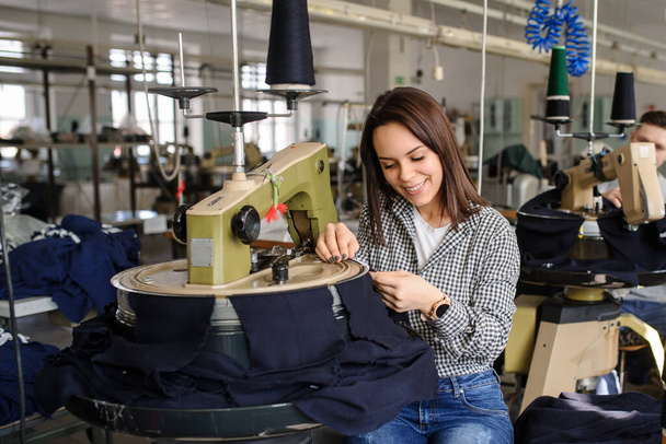 foto de cerca de una joven mujer que trabaja con la máquina de enlace para tejer en la industria textil - Foto, Imagen