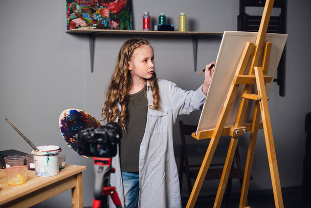 une jeune artiste mignonne enregistre une histoire pour son blog vidéo dans un atelier dans une école d'art. - Photo, image
