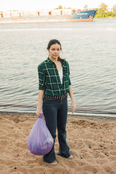 Taking care of our planet, fighting plastic garbage in nature. A young female volunteer - Foto, afbeelding