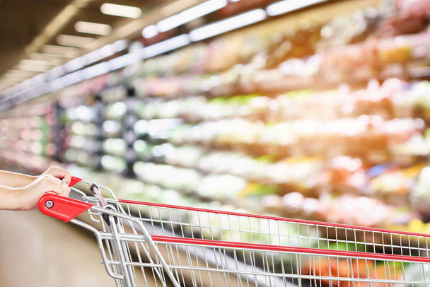 nő kézi bevásárlókosár elmosódott szupermarket friss termék polcok háttér - Fotó, kép