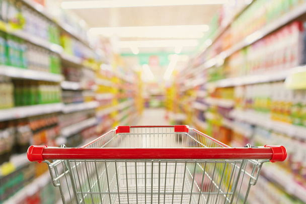 Supermercado corredor interior borrão fundo com vazio carrinho de compras vermelho - Foto, Imagem