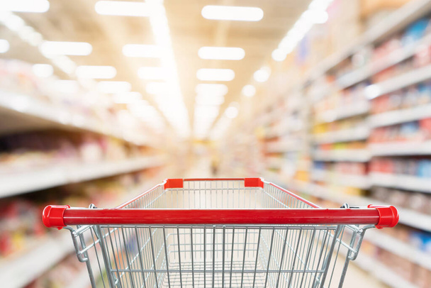 Supermarket aisle blurred background with empty red shopping cart - Photo, Image