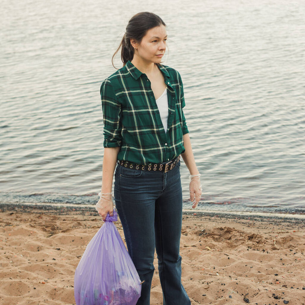 Taking care of our planet, fighting plastic garbage in nature. A young female volunteer - Valokuva, kuva