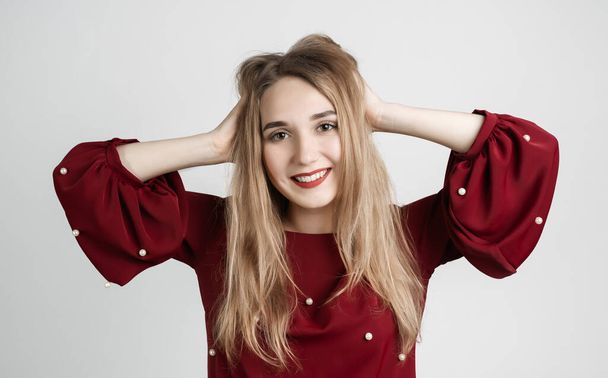 Pretty carefree modern girl with long blonde hair holding to her head or touching hair. Isolated on white background. Emotions, expressions, hairstyle and people concept. - Zdjęcie, obraz