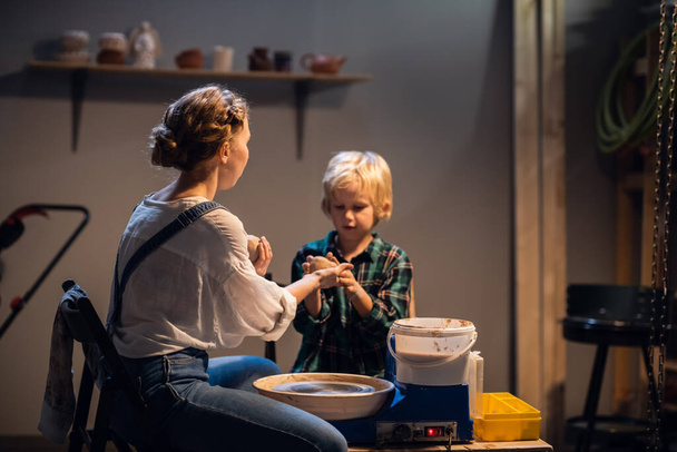 a beautiful woman teacher in her workshop conducts a lesson in clay modeling for a little boy. - Fotografie, Obrázek