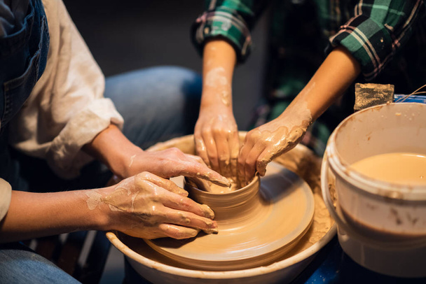 una lezione di ceramica in una scuola d'arte è insegnata da una giovane ragazza un vasaio per un bambino carino. - Foto, immagini