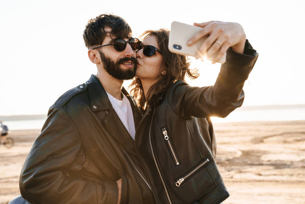 Beautiful young lovely couple spending time amazing time at the sunny beach, taking a selfie - Fotoğraf, Görsel