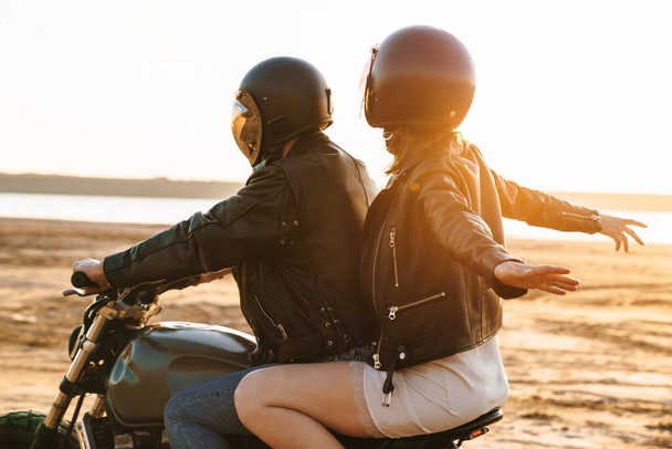 Beautiful young stylish couple enjoying ride on a motorbike at the beach - Φωτογραφία, εικόνα