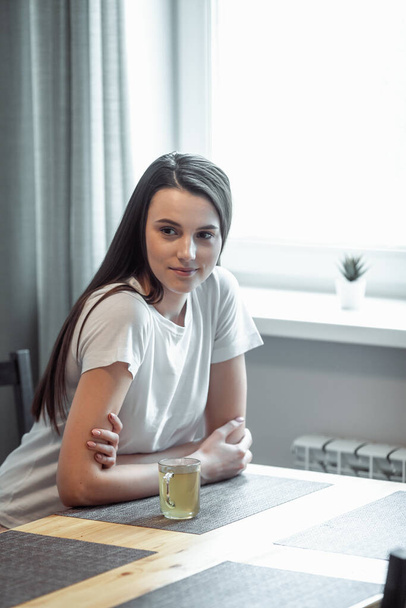 beautiful young woman drinking hot beverage. Attractive girl relaxing at home - Fotó, kép