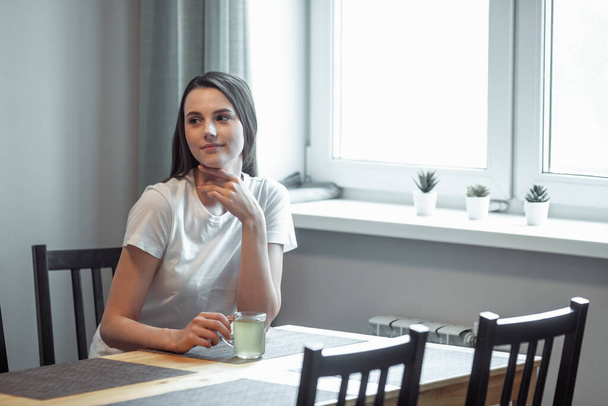 beautiful young woman drinking hot beverage. Attractive girl relaxing at home - Zdjęcie, obraz