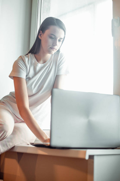 Girl working on computer laptop in light room. Woman chat in social network via net-book in modern interior - Fotó, kép