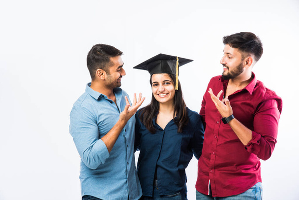Mooie jonge Graduate Indiase meisje student vieren succes met mannelijke vriend tijdens het dragen van afstuderen ceremonie Hoed tegen witte achtergrond - Foto, afbeelding